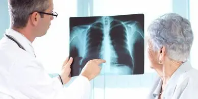 A doctor pointing to an x-ray of someone 's chest.